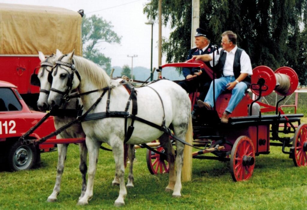 Historische Handdruckspritze auf einem Holzwagen mit Deichsel für ein Pferdegespann
