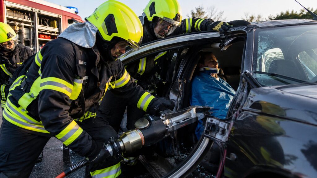 Feuerwehrleute befreien mit hydraulischem Rettungsgerät eine eingeklemmte Person aus einem Unfallfahrzeug